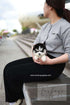 Person holding a small black and white puppy outdoors with a blurred background